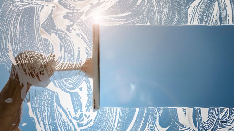 Professional window cleaner demonstrating proper squeegee technique for streak-free glass cleaning results