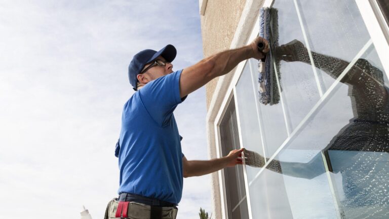 Hero image of a window cleaner quoting a job with tablet, building facade reflections, and pricing overlay ranges