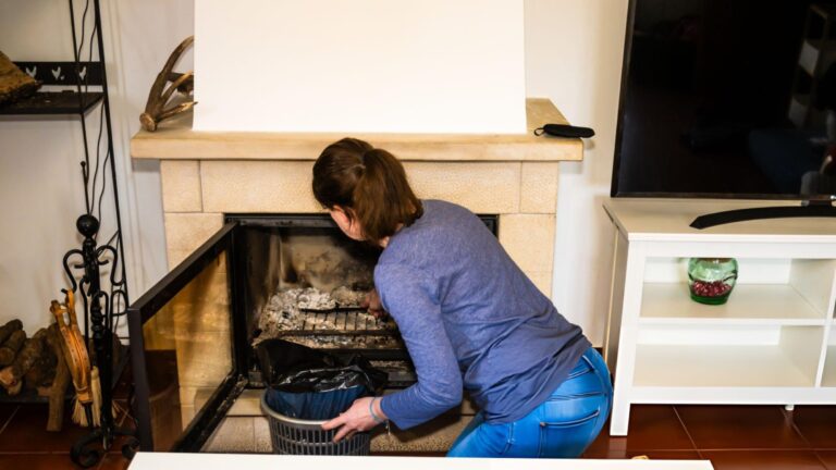Homeowner cleaning fireplace chimney with professional brush and rods to remove dangerous creosote buildup and prevent chimney fires