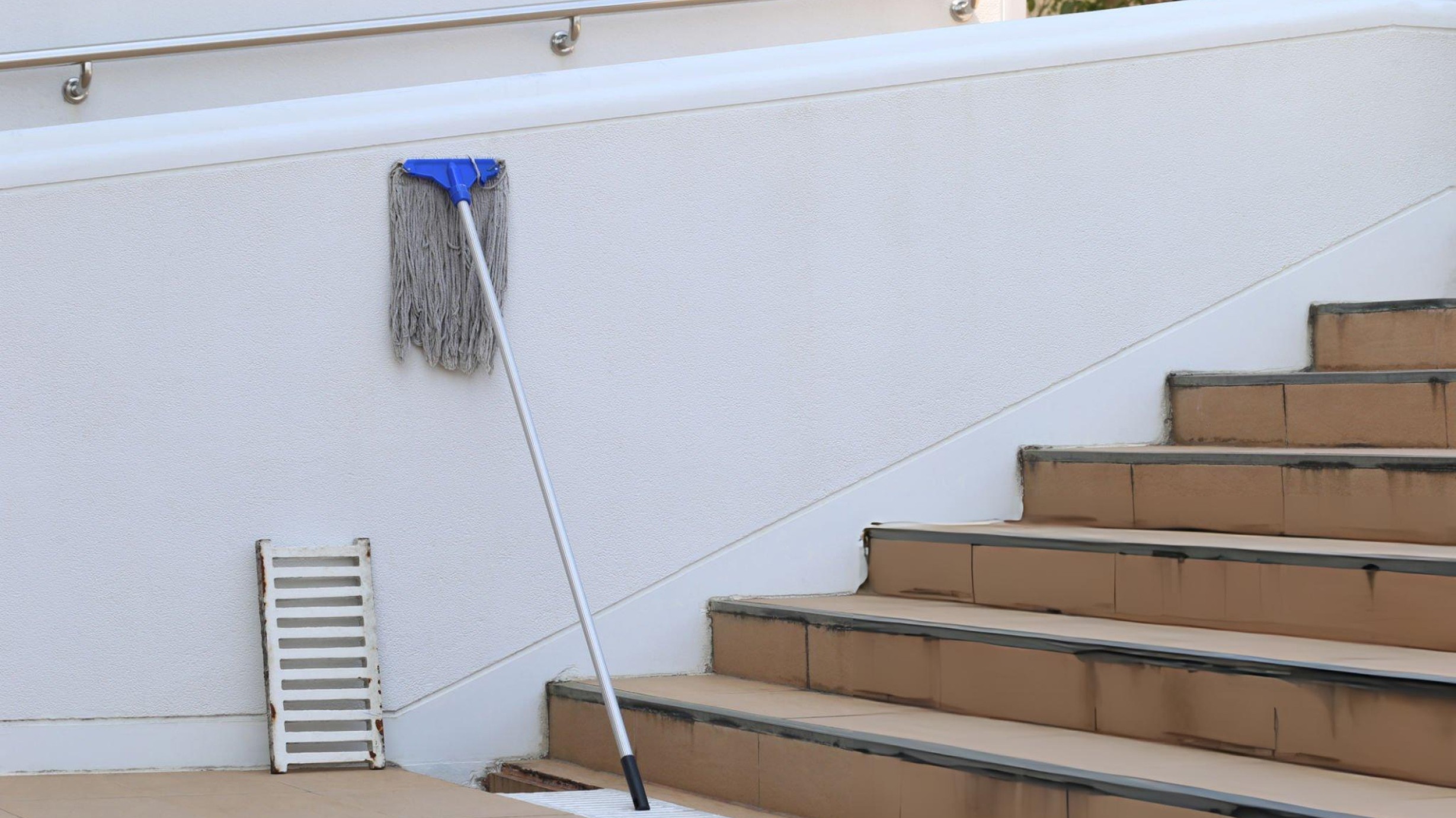 A dry mop and a wet mop placed side by side on a clean floor, showing their difference in appearance and use.