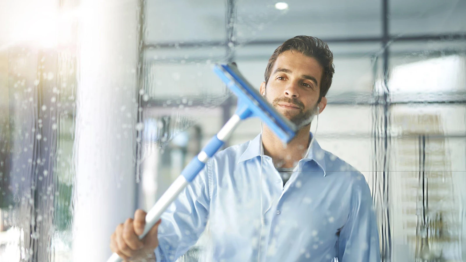 Floor squeegee pushing water across a tiled floor after cleaning